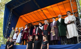 Zdjęcie grupowe uczestników wydarzenia podczas występu na scenie.