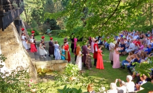 Zdjęcie grupowe uczestników wydarzenia. Uczestnicy przebrani w kostiumy z epoki bawią się dworskim ogrodzie.