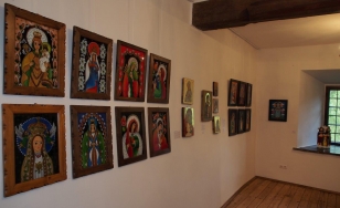 Zdjęcie przedstawia jedno z pomieszczeń wystawy. Na ścianach wiszą obrazy oraz ikony.
