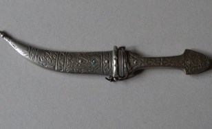 Zdjęcie przedstawia zabytkowy kindżał, czyli rodzaj długiego noża. Stosowany mógł być jako broń biała, ceremonialna bądź narzędzie.