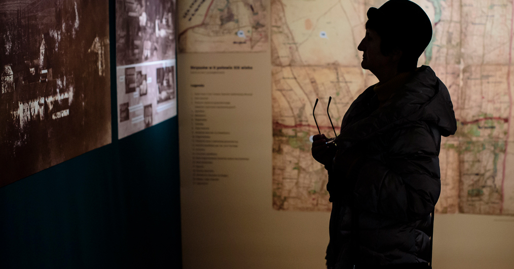 Kobieta ogląda mapę wyeksponowaną w muzeum, skupiona na szczegółach i otoczeniu.
