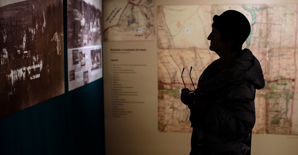 Kobieta ogląda mapę wyeksponowaną w muzeum, skupiona na szczegółach i otoczeniu.
